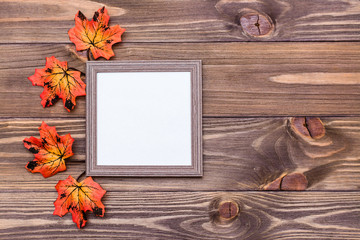 Naklejka na ściany i meble Ready mock up blank photo frame on brown wooden background surrounded by orange maple leaves. Copy space