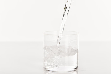 clear fresh water pouring into glass isolated on white