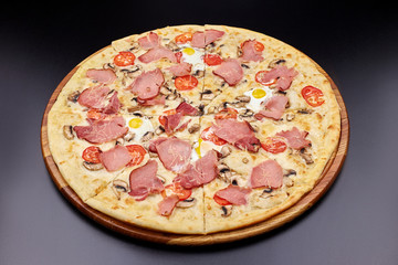 Carbonara pizza with bacon and egg on beautiful grey table. Isolated on dark background.
