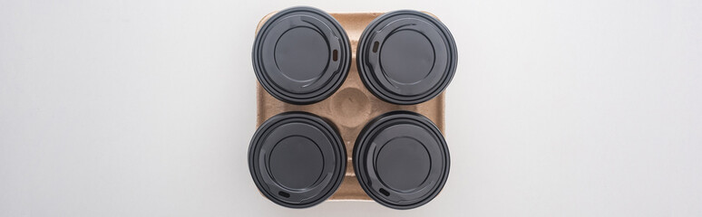 panoramic shot of paper cups with coffee in cardboard tray on white background