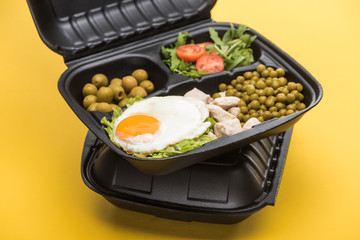 eco package with vegetables, meat, fried egg and salad isolated on yellow