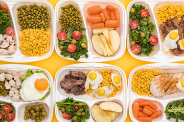 top view of eco packages with apples, vegetables, meat, fried eggs and salads isolated on yellow