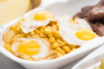 selective focus of eco package with corn and fried eggs on white background