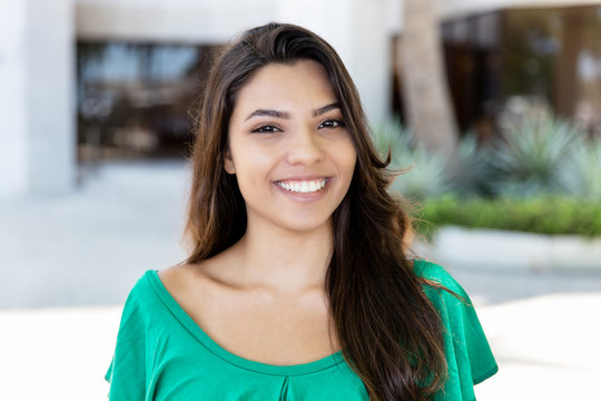 Portrait of laughing latin american young adult woman with long dark hair