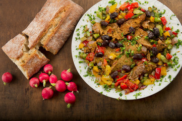 A plate of seitan with vegetables, homemade bread and fresh radishes
