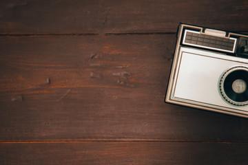 Silver retro vintage metal film camera top view on dark brown wood texture table desk background