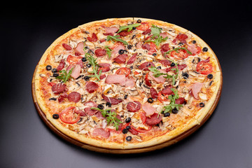 Fresh pizza Campania on wooden cutting board. isolated on dark background.