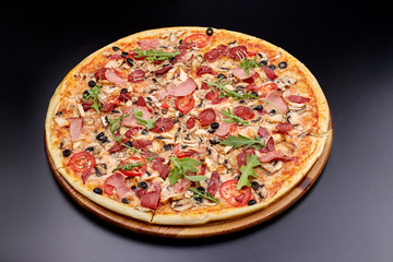 Fresh pizza Campania on wooden cutting board. isolated on dark background.