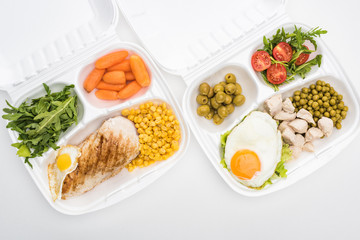 top view of eco packages with arugula, vegetables, meat, fried eggs and salad on white background