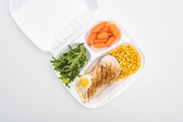 top view of eco package with vegetables, meat, fried egg and arugula on white background