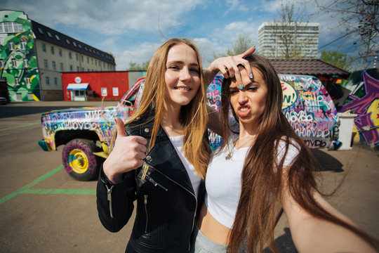 two very cute young girls posing as top models on a street in Europe on vacation,sisters actively posing on a sunny summer day ,very happy and joyful people