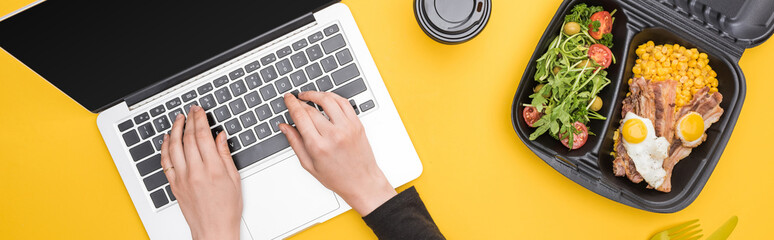 panoramic shot of woman using laptop with eco package isolated on yellow
