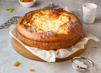 Open pie with cottage cheese filling on a wooden cutting board with milk. Healthy children breakfast or snack.