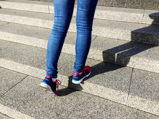 Young sport woman running up on stone stairs with sun spot background. Healthy lifestyle, workout and diet concept.