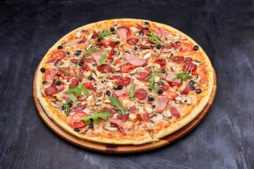 Fresh pizza Campania on wooden cutting board. isolated on dark background.