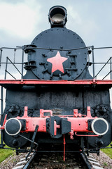 Old Russian locomotive. Steam locomotive with red wheels. Retro locomotive on rails. Black locomotive with red star.