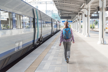 Young woman walking along platform to catch train. Rail travel