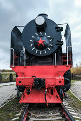 Old Russian locomotive. Steam locomotive with red wheels. Retro locomotive on rails. Black locomotive with red star.