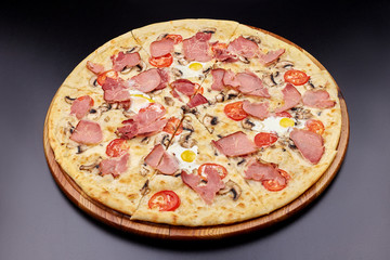 Carbonara pizza with bacon and egg on beautiful grey table. Isolated on dark background.