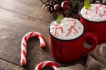 Peppermint coffee mocha decorated with candy canes for Christmas on wooden table. Copy space