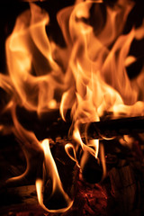 Burning wood at night. Campfire at touristic camp in nature in mountains. Flame and fire sparks on dark abstract background.