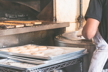 USA, New york: Traditional bagel bakery. Baker in the process of preparing authentic New York style bagels with sesame for baking in the oven.