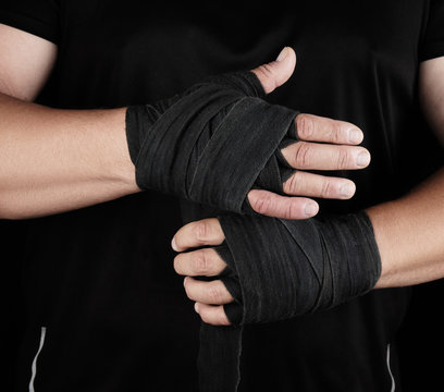 man wraps his hands in black textile bandage for sports
