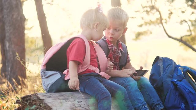 happy family a boy scout children tourists search navigation on a digital smartphone tourists with backpacks teamwork slow motion video concept. brother and sister looking for lifestyle a way hiking