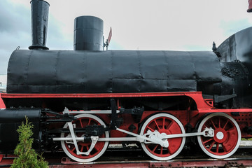 Fototapeta na wymiar Old Russian train has been made on 1900. Old Russian locomotive. Steam locomotive with red wheels. Retro locomotive on rails.