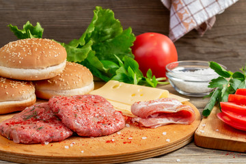 Process of cooking homemade burgers, meatballs, tomatoes, cheese and other ingredients on a wooden background