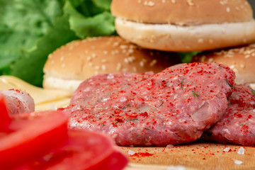 Process of cooking homemade burgers, meatballs, tomatoes, cheese and other ingredients on a wooden background, close up