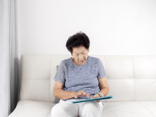 Asian senior woman using tablet at home, lifestyle concept.