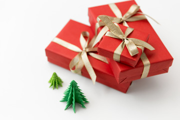 winter holidays, new year and celebration concept - red gift boxes and origami christmas trees on white background