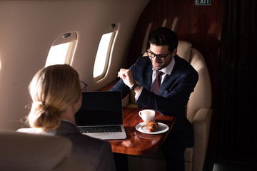 executive businesspeople working together with laptop in airplane