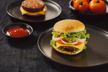 Hamburger with beef meat burger and fresh vegetables on dark background. Tasty fast food