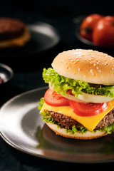 Fresh Tasty burger on cutting board with with french fries, ketchup and cola in glass over black background