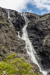 Fototapeta na wymiar Norwegian mountain road. Trollstigen. Stigfossen waterfall over the Norway tourist landscape valley.
