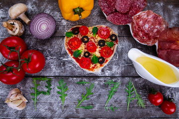Heart shaped pizza ingredients. The name of the pizza is written in arugula.