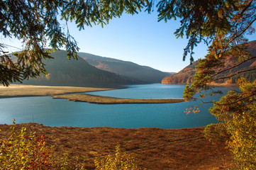 Nature background, lake in mountains covered with autumn forest
