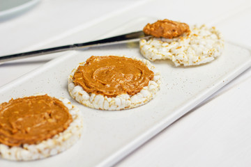 crunchy natural peanut butter sandwich with rice cake bread and knife with peanut butter on wooden surface. Proper nutrition diet vegetarian breakfast