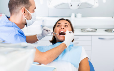Obraz premium Dentist is treating woman patient which is sitting in dental chair