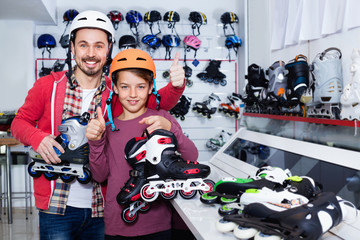 Father and son showing roller-skates they bought in sports store