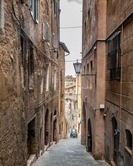 Cobbled Alley between Old Buildings In Siena Italy