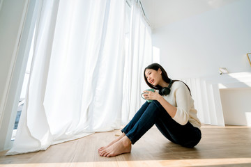 happiness beauty asian woman enjoy song music with headphone full body on wooden laminate floor in living room