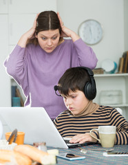 Upset mother arguing with son who plaing video games