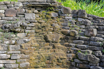 A wall of stone covered with grass and moss