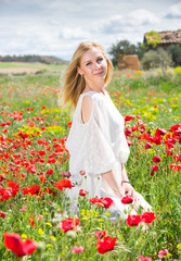 Naklejka na ściany i meble Portrait of young woman in white dress posing in poppies plant