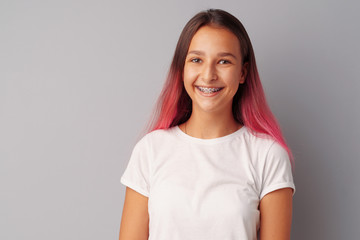 Young girl teenager with pink hair happy and smiling over gray background - obrazy, fototapety, plakaty