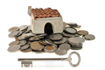 Maison sur des pièces de monnaie avec une clé au premier plan