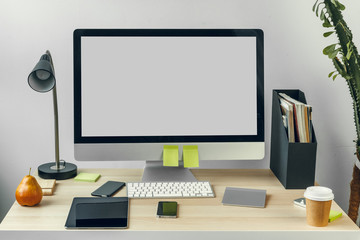Computer monitor with mockup white screen on office table with supplies